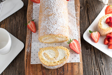Swiss roll homemade baked with whipped cream filling and strawberries