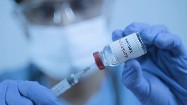 extreme close up shot of doctor with Monkey pox vaccine or antiviral drug using with syringe at hospital for treatment.