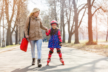 Mother and her daughter wearing roller skates in park