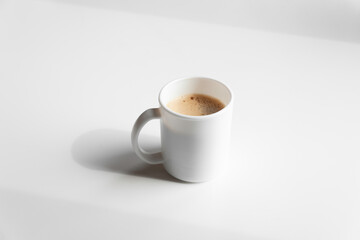 Cup of fresh crema espresso with bubble and froth on white empty table or background.