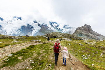 Fototapeta premium Mother and to children going for a walk in mountain surroundings