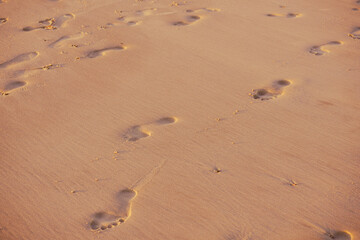 Human footprints on brown beach sand.