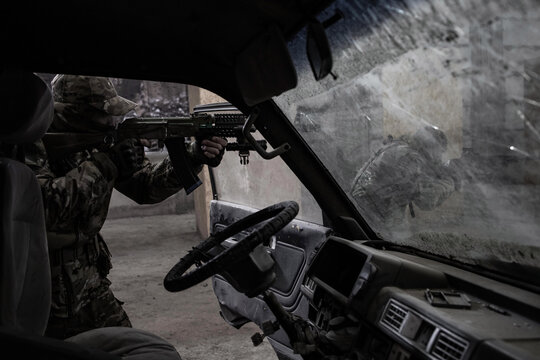 Two soldiers in camouflage and with guns next to the wrecked car. Airsoft Players.