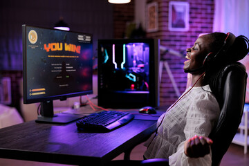 Female player celebrating successful video games online win, using computer to stream gameplay....