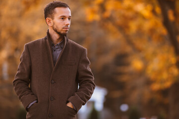 young man looks thoughtfully to the side, walking in the park