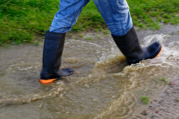 A person is splashing through a puddle in gumboots