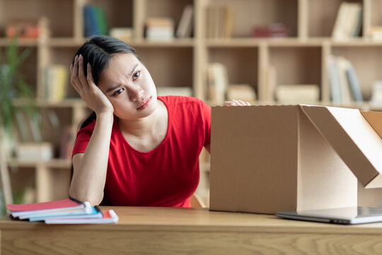 Unhappy sad disappointed teen girl sitting with cardboard box in living room interior
