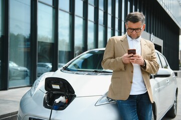 a businessman charges an electric car