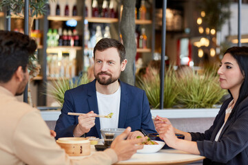 Group of business people enjoying Asian food during business lunch hour in shopping mall cafe