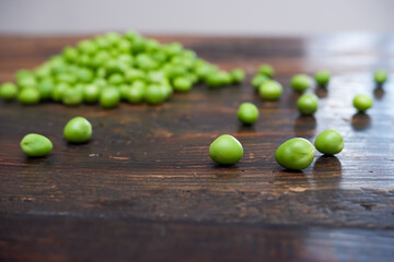 Fresh peeled green pease on a brown wooden table with copy space. Still life of green peas in pods with pea shoots on wooden table
