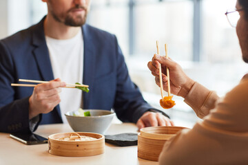 Closeup of businessman enjoying Asian food during business lunch with colleague at cafe, copy space