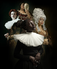 Adorable women as medieval royalty persons in vintage outfits posing on dark background. Concept of...