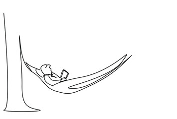 man lying in hammock on tree in garden on vacation reading a book calmly and focused