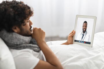 Man having video call with doctor while staying in bed