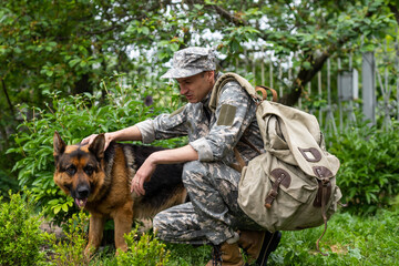Man in military uniform with German shepherd dog, outdoors.