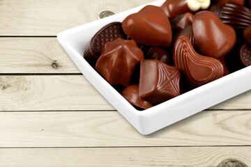 Heart shaped box with tasty chocolate candies on desk.