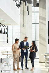 Minimal full length portrait of three business people talking in graphic white interior