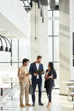 Minimal Full Length Portrait Of Three Business People Talking In Graphic White Interior