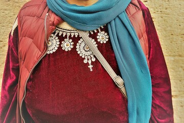 Oberkörper von arabischer Frau mit rotem Samtkleid mit weißen Ornamenten, blauem Schal und roter...