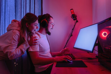 Young couple in room with neon light are using modern personal computer