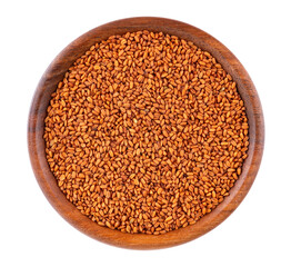 Camelina sativa seeds in wooden bowl, isolated on white background. Seeds of camelina or false flax. Raw material for camelina oil. Top view.