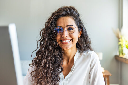 Successful businesswoman standing in creative office and looking at camera. Young latin woman entrepreneur in a coworking space smiling. Portrait of beautiful business woman