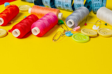 Sewing accessories on a yellow background. Closeup. Copy space