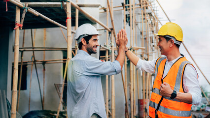 Architect and engineer construction team giving hightfive after successful work at outdoors construction site, success collaboration concept.