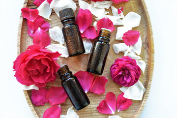 Essential oil of rose in a bottle and fresh flowers on a wooden table Natural cosmetics and aromatherapy