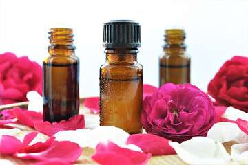 Essential oil of rose in a bottle and fresh flowers on a wooden table Natural cosmetics and aromatherapy