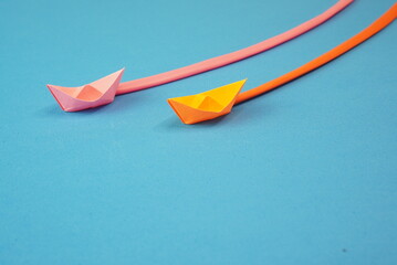 Little red paper boats sail in search of new goals concept, on a blue sea background, they leave...