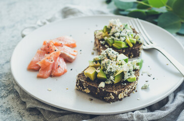 Healthy breakfast with salmon and toasts with rye bread, avocado and blue cheese