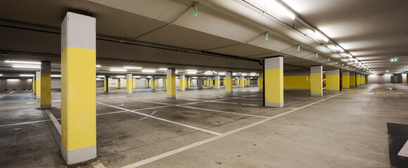 Empty underground supermarket parking lot with yellow concrete columns and white stripes for cars