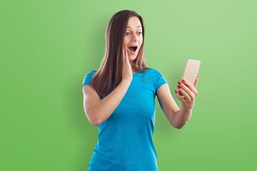 Cheerful amazed girl with device gadget on green color background
