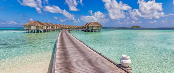 Sunny Maldives island, luxury water villas resort and wooden pier. Beautiful sky and clouds and...