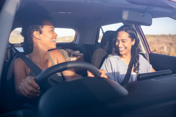 Woman friends in car laughing while driving