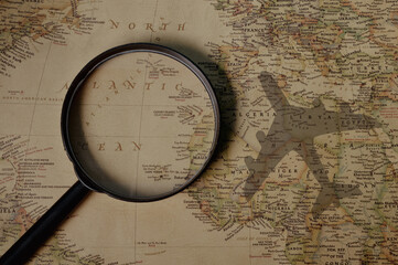 Magnifying glass on world travel map with airplane