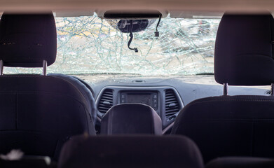 Damaged car window after an accident. Broken windshield as a result of an accident, inside view. Cabin interior details, view from the cab. Safe movement. Broken windshield. Glass crack and damage.