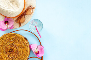 Flatlay of beach accessories with straw hat and rattan bag. Summer beach background