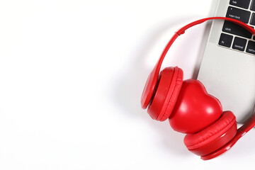 Red headphones with red heart placed on a laptop isolated on white background. Flat Lay photography with copy space.