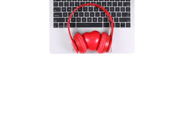 Red headphones with red heart placed on a laptop isolated on white background. Flat Lay photography with copy space.