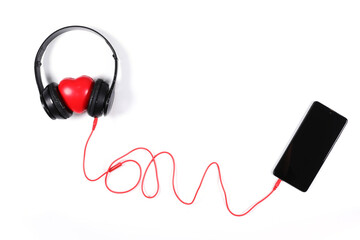 Black headphone connected to mobile phone with red heart isolated on white background. Flat lay photography has copy space.