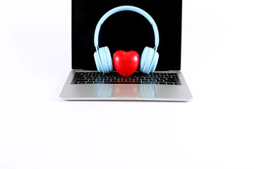 Light blue headphone with red heart placed on a laptop isolated on white background have copy space.