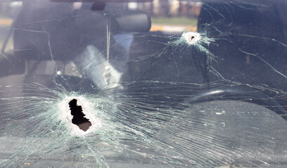 Holes on the windshield of the car, it was shot from a firearm. Bullet holes. Smash car windshield,...