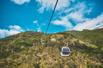 Modular cabins cable car against the bright sky, clouds ans mountains. Cableway - one of the...