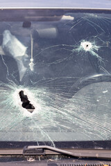Holes on the windshield of the car, it was shot from a firearm. Bullet holes. Smash car windshield,...