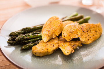 fried chicken breast pieces with asparagus on plate