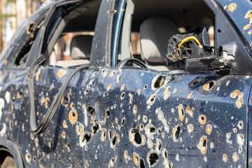Fototapeta na wymiar Car riddled with bullets. War of Russia against Ukraine. A car of civilians shot by the Russian military during the evacuation of women and children. Traces of bullets and fragments of shells.