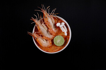 Tom Yum kung spicy. Tom Yum kung in a white bowl on a dark black background, top view, copy space.