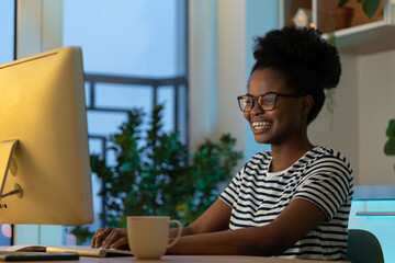 Happy smiling designer girl enjoy working from home on new remote project. Successful african web developer coding new program, website or software. Young freelance black woman on distance occupation
